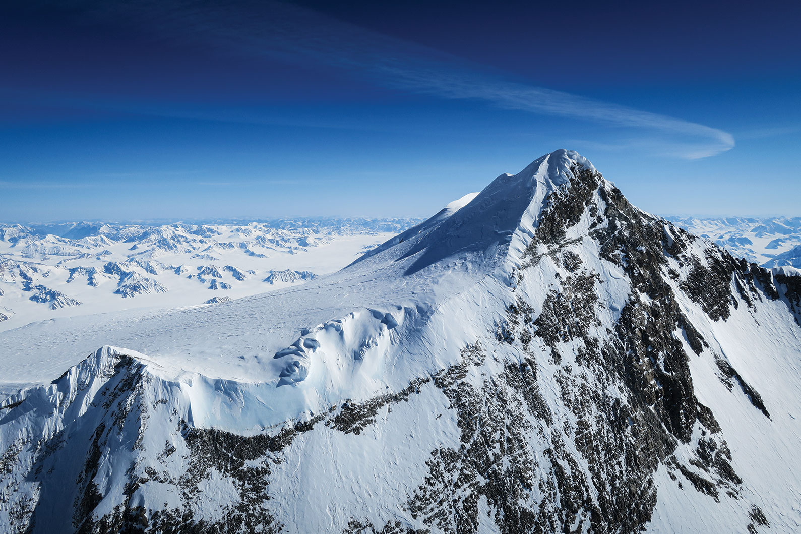 Logan main summit snow covered mountain peak with vast open blue sky